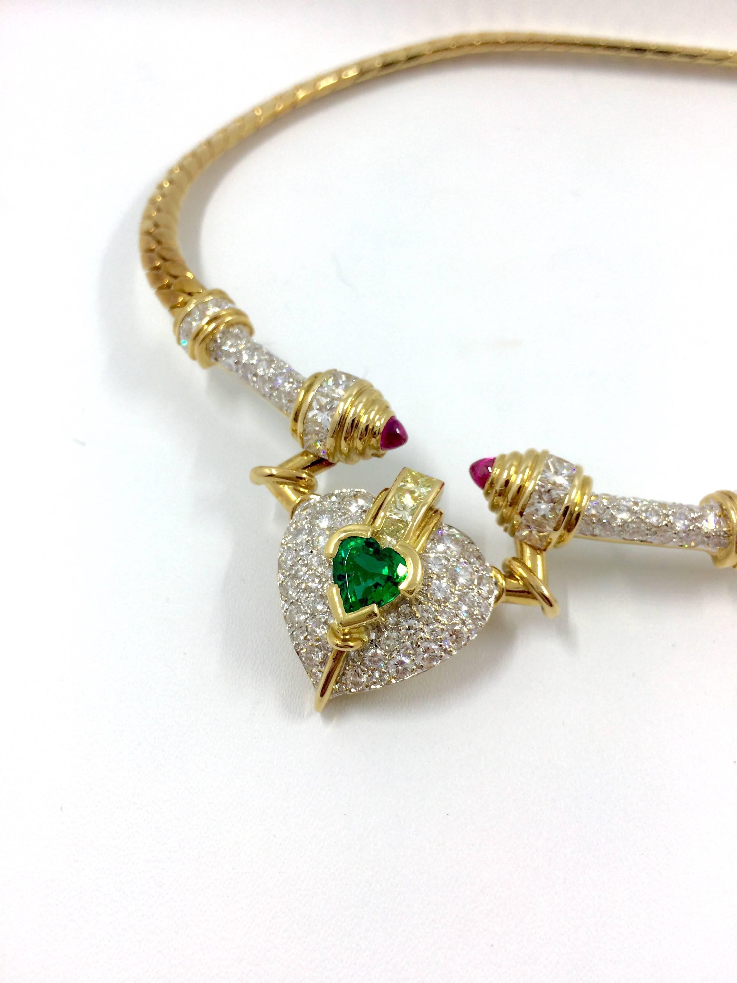 An unique yellow gold necklace set in the middle with a heart cut emerald surrounded by brilliant cut diamonds. 
3 princess cut fancy yellow diamonds are setted above the emerald.
The ends of the necklace set with a cabochon cut pink sapphire, 8