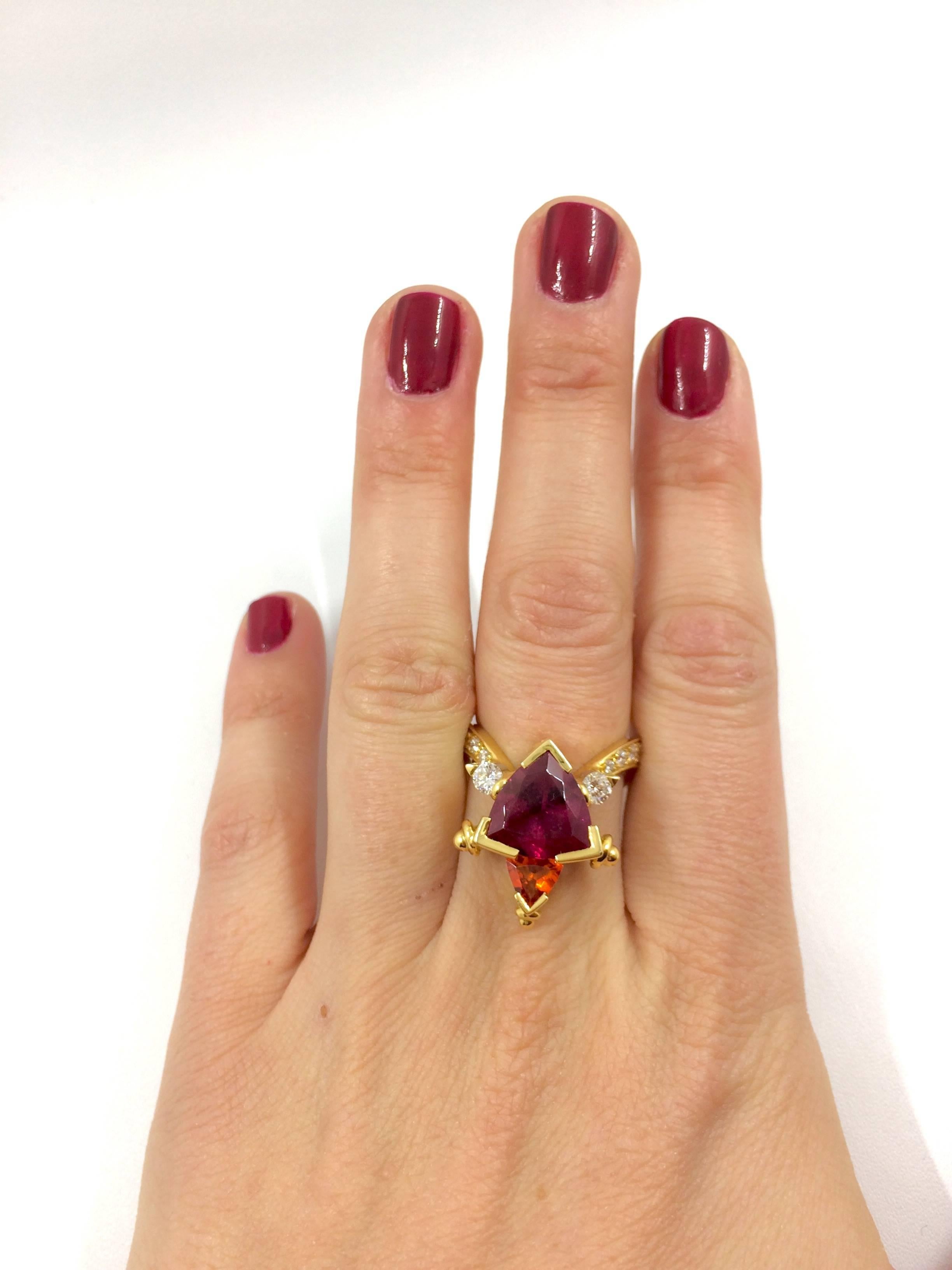 A yellow gold ring set in the middle with a stunning rubelite surmounted by a mandarin garnet. Six brilliant cut diamonds surrounded the rubelite on each side. The ring's body is waved like a swan. 
The ring is an unique creation entirely