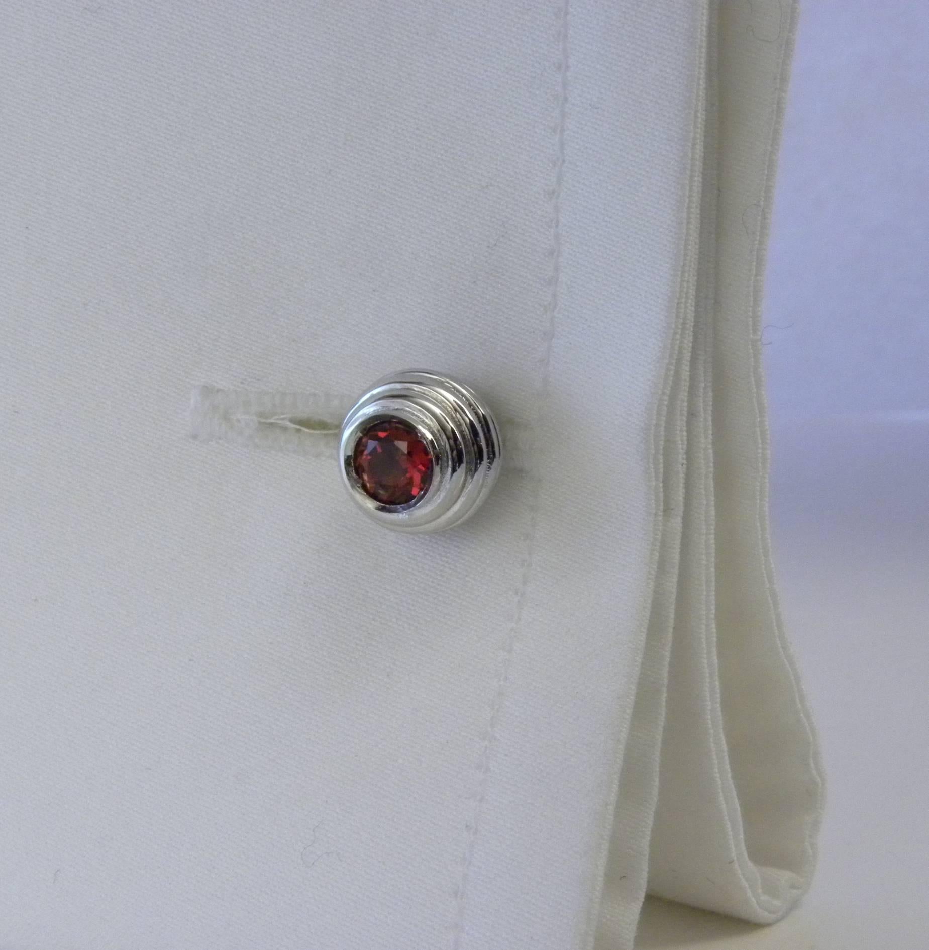 A set of cufflinks and 4 stud combining the white of sterling silver with the vivid red of spessartine, a precious garnet variety.
In our smart Black Box and Pouch