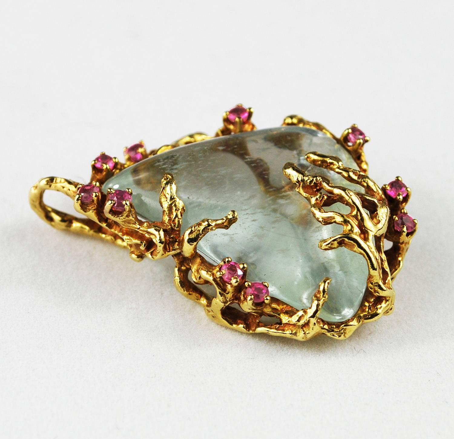 One of the kind a pale-blue quartz pendant in 18k gold with rubies made by famous jewelry designer Arthur King, ca 1960.

The smooth polished beautiful stone is surrounded by ten faceted fuchsia rubies. Impressed mark on back 