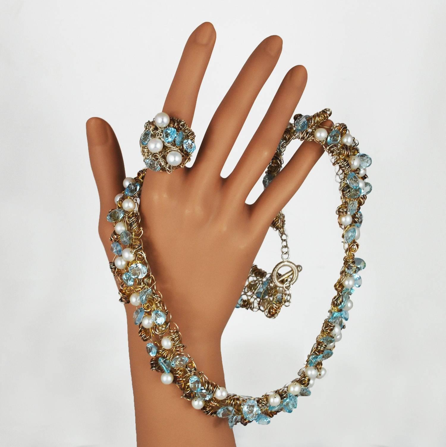 A bright aquamarine pearl necklace and ring set  from American jewelry designer Nikki Fledbaum, or Sedacca. A total of 53 pearls and 69 cut aquamarine stones are strung on rhodium wire and set amongst tightly wound whimsical spirals, all hand made.