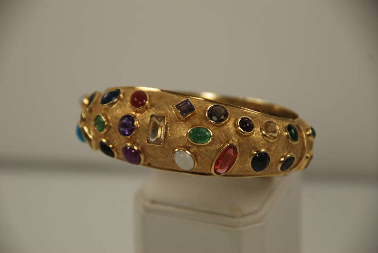Fabulous 18k gold bangle bracelet set with many, many different gem stones in all shapes and sizes. There are opals, citrines, amethysts, turquoise, star rubies, garnets, sapphires, etc. There are both cut stones and cabochon stones. Each stone is