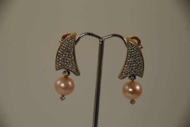 Unique diamond, 18k gold, and pearl earrings. The pearls on these earrings have a beautiful luster and the diamonds are white and sparkly. There are approximately 2.25carats of diamonds total. The pearls are approx. 9mm. The earrings lay well on the