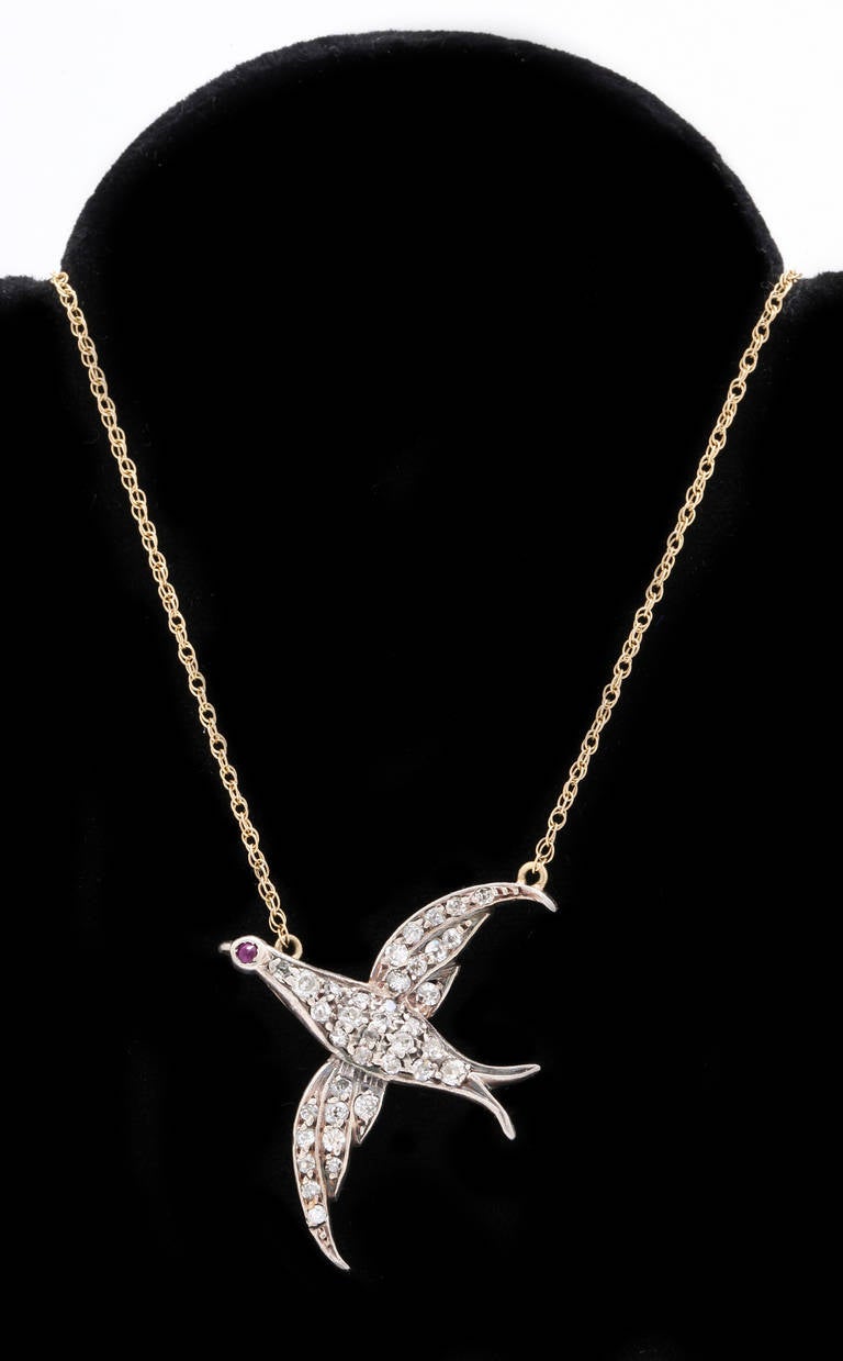 Early Victorian rose cut diamond bird pendant set in 18k gold on the back and silver on top. The eye of the bird is a ruby. The antique bird is attached to a contemporary 14k gold chain. The bird was probably a pin that has been re-purposed. It is a