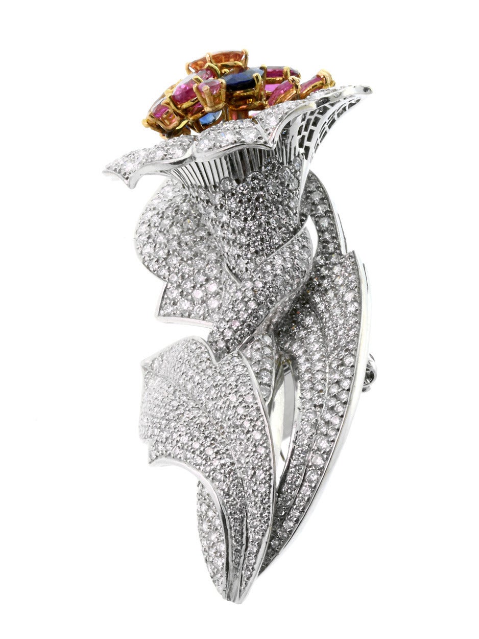 A magnificent diamond brooch featuring 11.80ct of Diamonds inset from one end of the floral design to the other, followed by 9.09ct of Sapphires and other semiprecious stones act as a bouquet of color near the top of this piece.

Made of 18k White