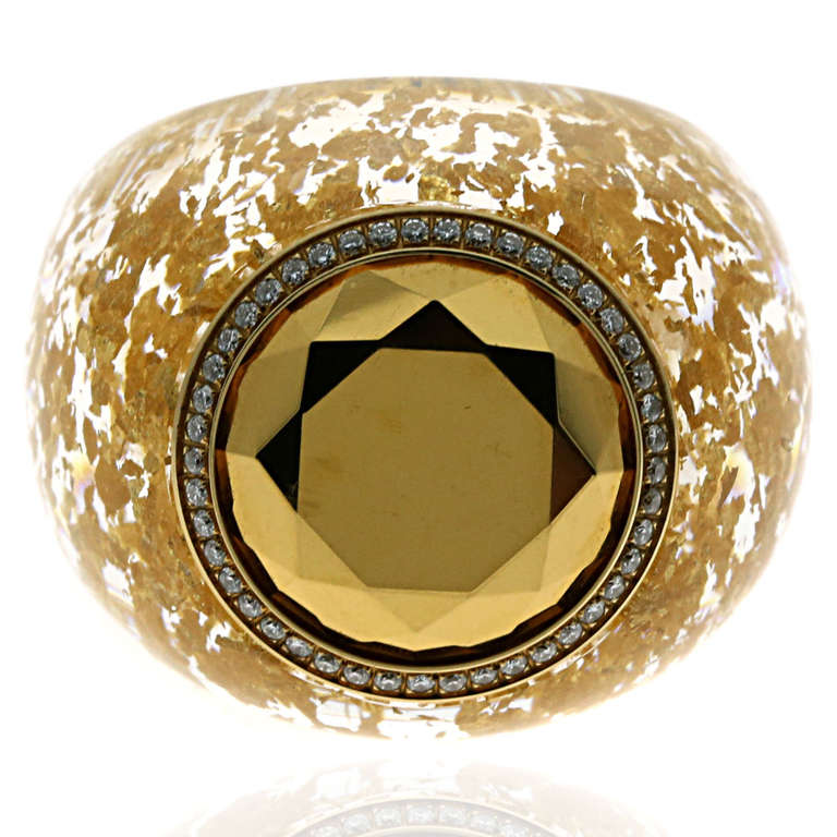 This stunning Chopard ring from the “Golden Diamonds” collection features a clear resin ring with scattered gold flakes embedded, followed by a titanium treated stone encased in 45 Round Brilliant Cut Diamonds.

Made of 18K Yellow Gold, Clear