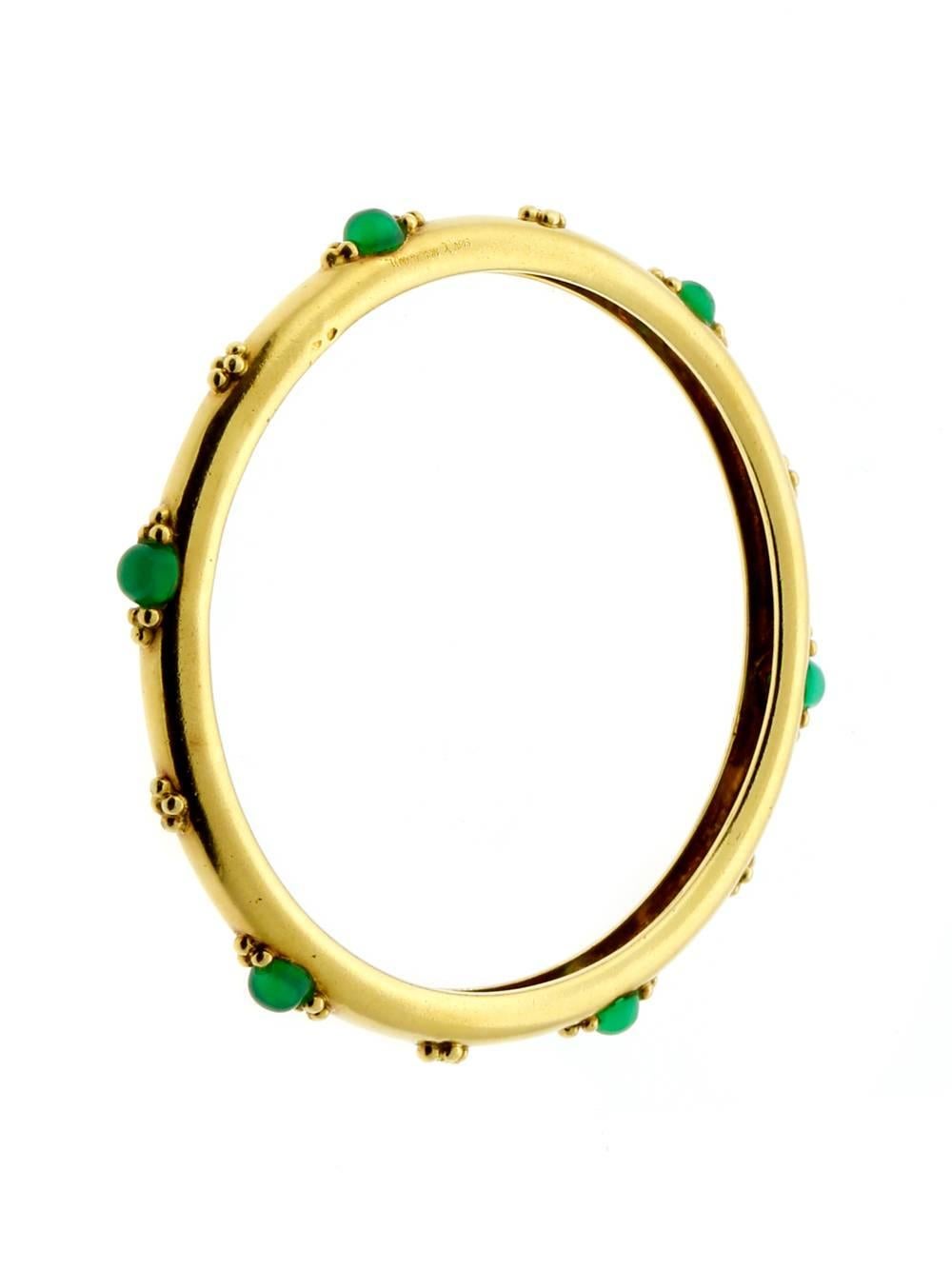 A classic 18k yellow gold bangle by Boucheron showing lovely patina, featuring 6 cabochon emeralds. The bracelets internal diameter is 2.25