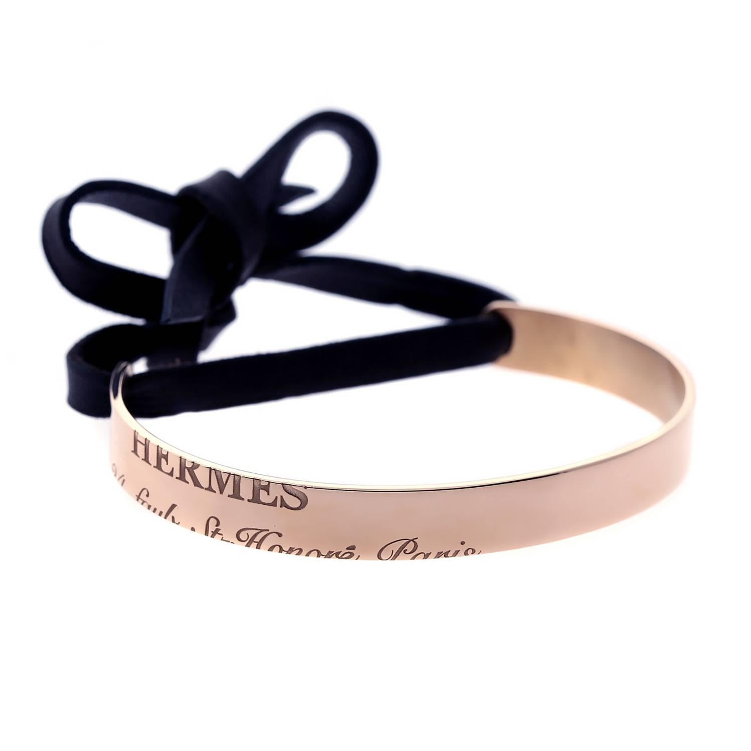 A chic authentic Hermes cuff featuring engravings of the brand maker and address in Paris in 18k rose gold, to seal the deal a contrasting black leather has been added which can be tied. Bracelet Length 16cm / 6.28in

This magnificent piece is