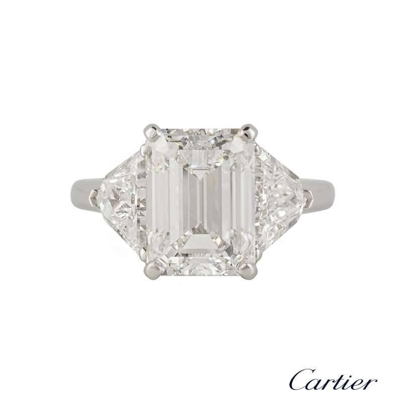 An exquisite diamond ring by Cartier. The central 5.03ct emerald cut diamond is F in colour and VS2 in clarity. The diamond is complimented by two trillion cut diamonds totalling 1.58ct, both well matched in colour and clarity. The ring is currently