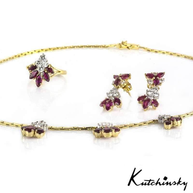 An ornate 18k yellow gold diamond and ruby suite by Kutchinsky. The 16 inch necklace is composed of 7 delicate diamond and ruby cluster drops, composed of 3 pear cut rubies, suspended from 4 round brilliant cut diamonds. The earrings are of a