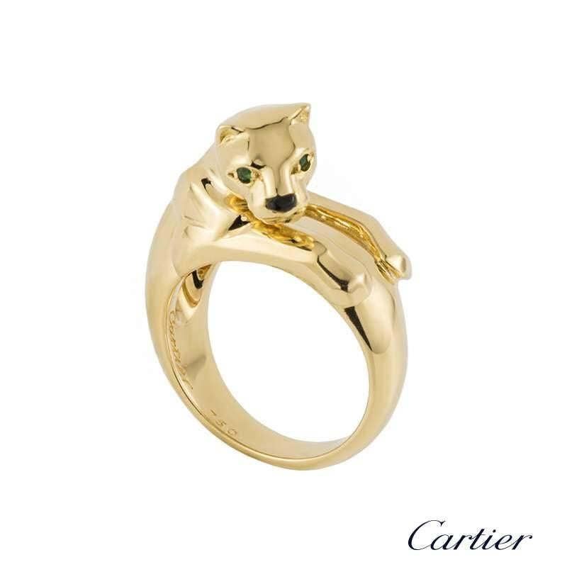 A beautiful 18k yellow gold panthere ring from the Panthere De Cartier collection by Cartier. The ring is composed of a panthere head motif and is complemented with two round emeralds set as the eyes and onyx for the nose with the body wrapping