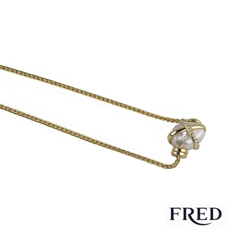 A beautiful 18k yellow gold pearl and diamond set necklace from the Baie des Anges collection by Fred. The necklace is set to the centre with a baroque shaped 11mm fresh water pearl, accentuated by a cross motif set to the top. The motif is pave set