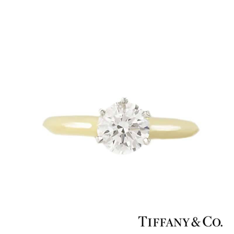 A classic 18k yellow gold and platinum diamond single stone ring by Tiffany & Co. The ring is set to the centre with a 0.91ct round brilliant cut diamond, H colour and VS1 in clarity and set in the iconic platinum six claw setting. Accentuating