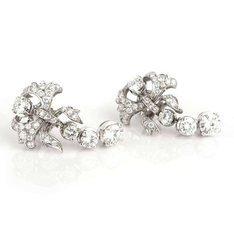 An elegant pair of diamond earrings of girandole design c.1950. Each earring is set with four round brilliant cut diamonds between 0.20ct-0.90ct, grain set with smaller diamonds in Platinum. The surmount is set with a 0.20ct diamond with a garland