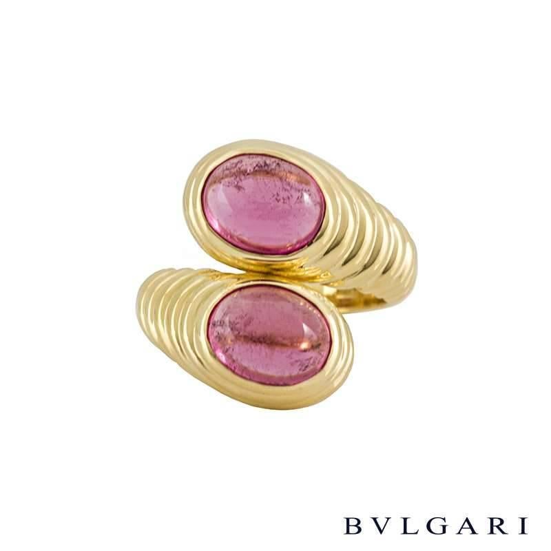 A contemporary 18k yellow gold dress ring by Bvlgari. The ring is composed of a wrap around design featuring two cabochon cut amethysts set to the front, complemented by circular ridges set to the shoulders. The tapered ring measures 2cm at its