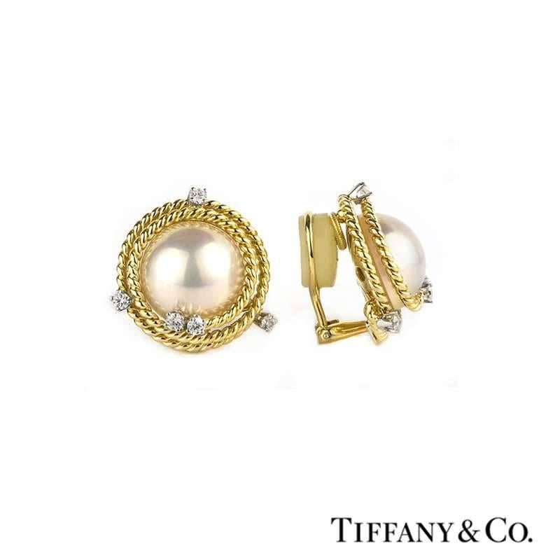 A pair of 18k yellow gold pearl and diamond earrings by Tiffany & Co. from the Jean Schlumberger collection. Each earring is comprised of a 15mm round mabe pearl, set in place by an 18k yellow gold rope design spiralling around the outer edge. 5