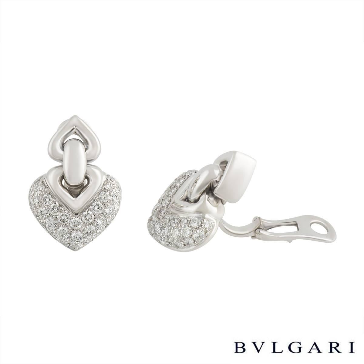 An iconic pair of Bvlgari 18k white gold pave diamond earrings from the Doppio Cuore collection. Each earring consists of an 18k white gold heart shaped drop section which is pave set with 32 round brilliant cut diamonds. This is connected to a