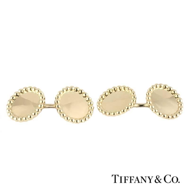 An elegant 14k yellow gold dress shirt studs and cufflinks set from Tiffany & Co. The set comprises of a pair of round double table cufflinks featuring a beaded outer edge and bar connections. The cufflinks are complemented by 3 matching dress