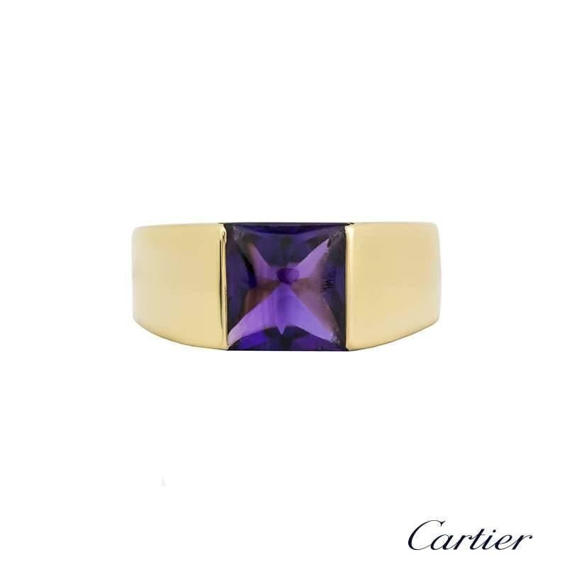 An 18k yellow gold ameythyst Tank ring by Cartier. The ring is set to the centre with a square cabochon cut ameythyst in a open tension setting. The tapered 4mm ring is currently a US size 6 1/2, EU size 53 and UK size N but can be adjusted for a