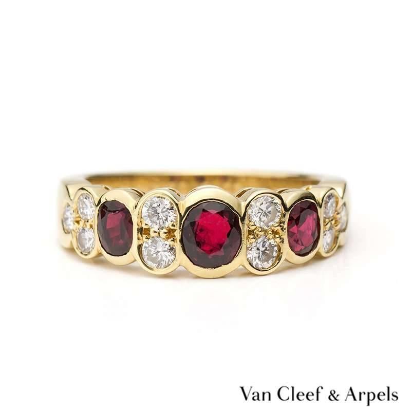 Van Cleef & Arpels 18k yellow gold half hoop design ring set with 3 oval rubies with brilliant cut diamond 2 stone spacers and trefoil cluster shoulders. The current size of this ring is a US size 5 1/2, EU size 50.5 and UK size L but can be