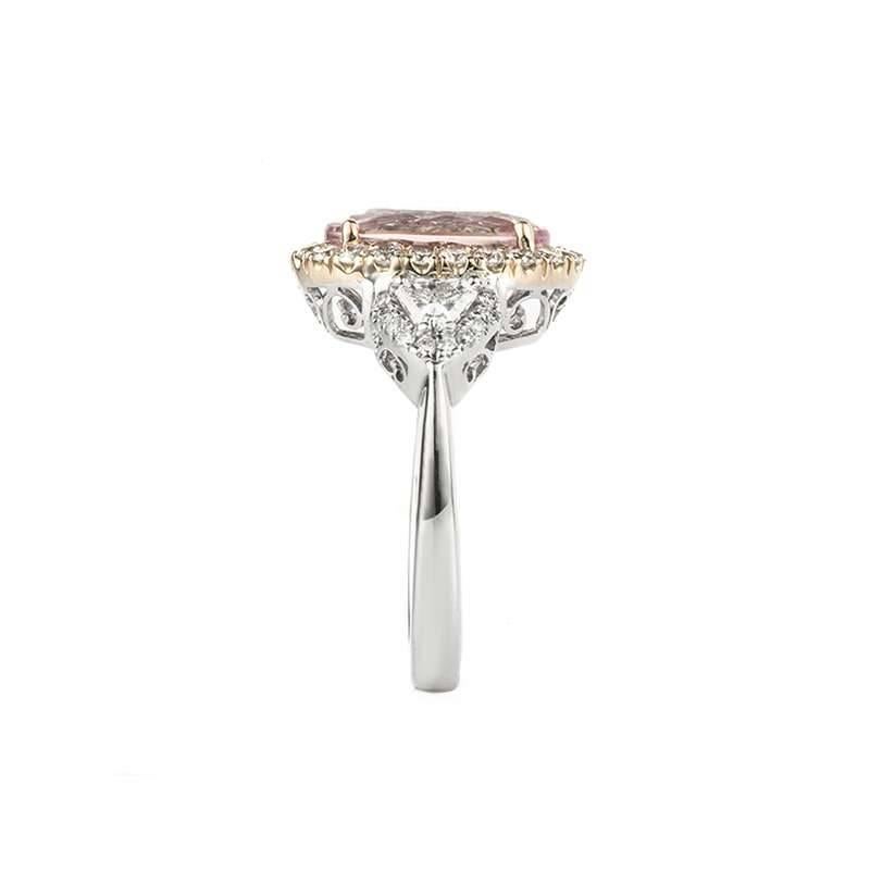 A morganite and diamond dress ring set in 18k white gold. The ring is set to the centre with an oval cut morganite, weighing approximately 4.14ct, displaying a pink even hue throughout, accentuated by a round brilliant cut diamond set halo.