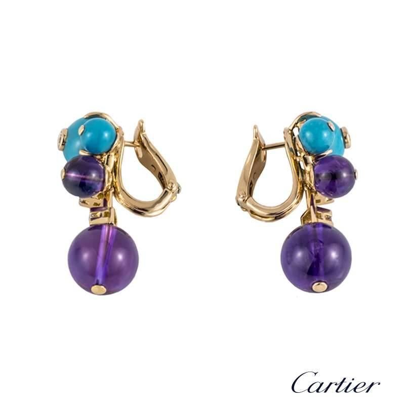 A beautiful pair of 18k rose gold drop earrings from the Les Delices collection by Cartier. Each earring is set to the front with a cluster of gemstones composing of turquoise, amethyst and round brilliant cut diamonds. Suspended from the cluster is