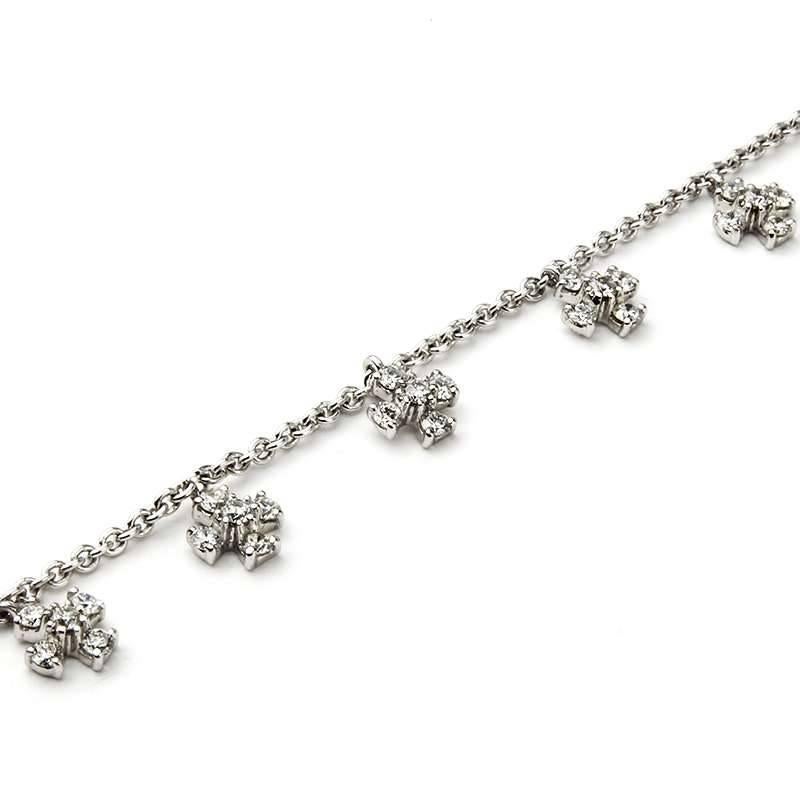 An 18k white gold diamond set bracelet. The bracelet is composed of 14 small crosses, each made up of four round brilliant cut diamonds totalling 1.28ct, colour G and VS in clarity, interspersed along the chain. The bracelet measures 7 inches in