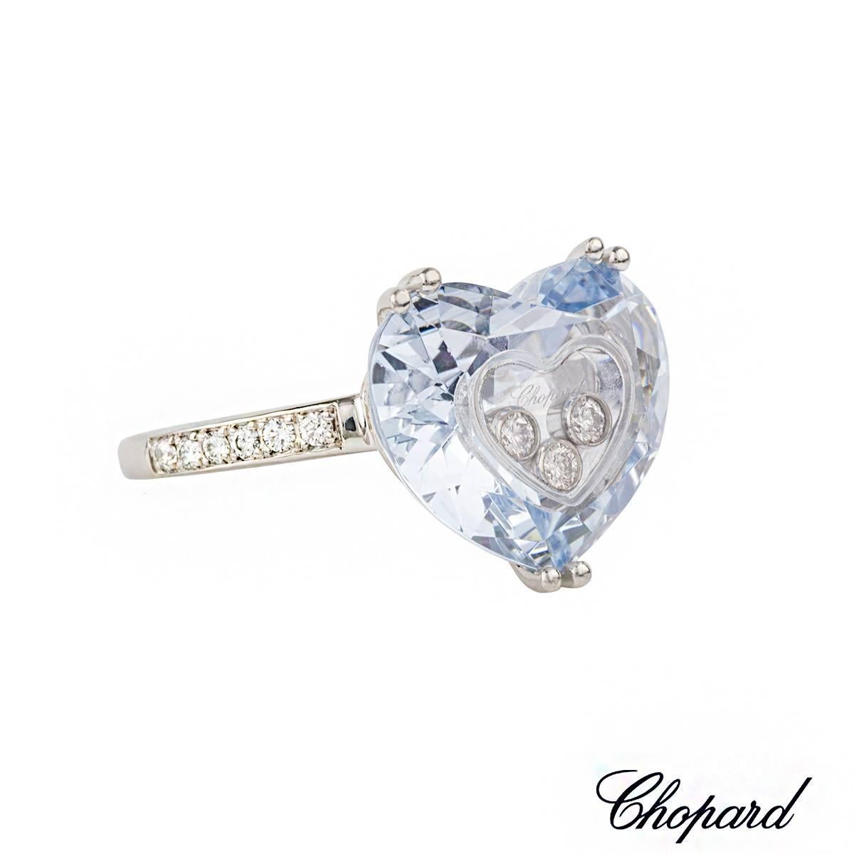 An 18k white gold ring from the Chopard happy Diamonds collection. The ring is composed of a blue glass heart motif encasing three round brilliant cut diamonds in the centre. The heart is complemented by pave set round brilliant cut diamond