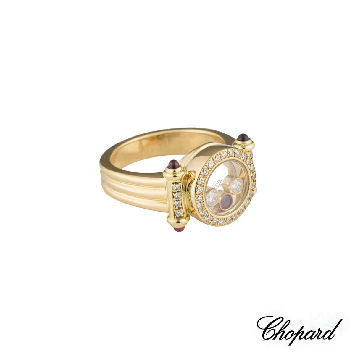A beautiful 18k yellow gold Chopard diamond and ruby ring from the Happy Diamonds collection. The ring comprises of a circular disk with a glass centre with 2 floating round brilliant cut diamonds and 1 round cut ruby in a rubover setting. The ring