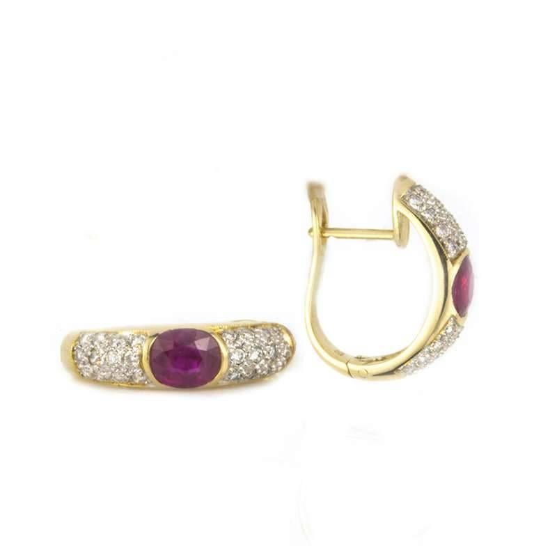 A pair of ruby and diamond earrings set in 18k yellow gold. Each earring is set to the centre with an oval cut ruby weighing 0.65ct, set between 24 pave set diamonds totalling 0.50ct.  The earrings have post clip fittings and are approximately 2cm