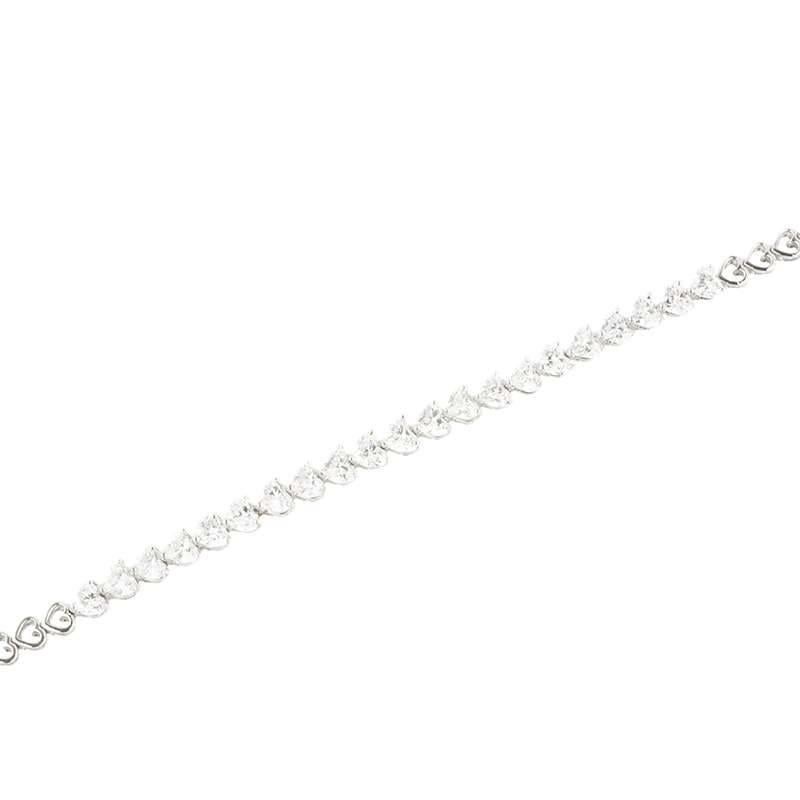 An 18k white gold diamond line bracelet. The bracelet comprises of 21 heart shape cut diamonds set to the centre of the bracelet each individually claw set totalling 5.15ct, F/G in colour and predominantly VS/SI in clarity. Accentuating the diamonds
