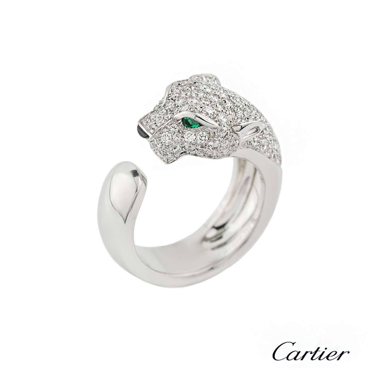A stunning 18k white gold Cartier diamond, onyx and emerald ring from the Panthere De Cartier collection. The ring is composed of a panthere head motif, pave set with 137 round brilliant cut diamonds totalling 1.15 carats, F+ colour and VS+ in