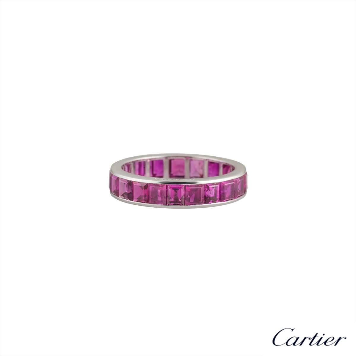 A stunning 18k white gold full eternity ring by Cartier. The ring is channel set throughout the centre with 22 square cut rubies, displaying a bright pink hue, totalling approximately 3.10ct. The 4.4mm wide ring is a US size 7, EU size 55 and UK