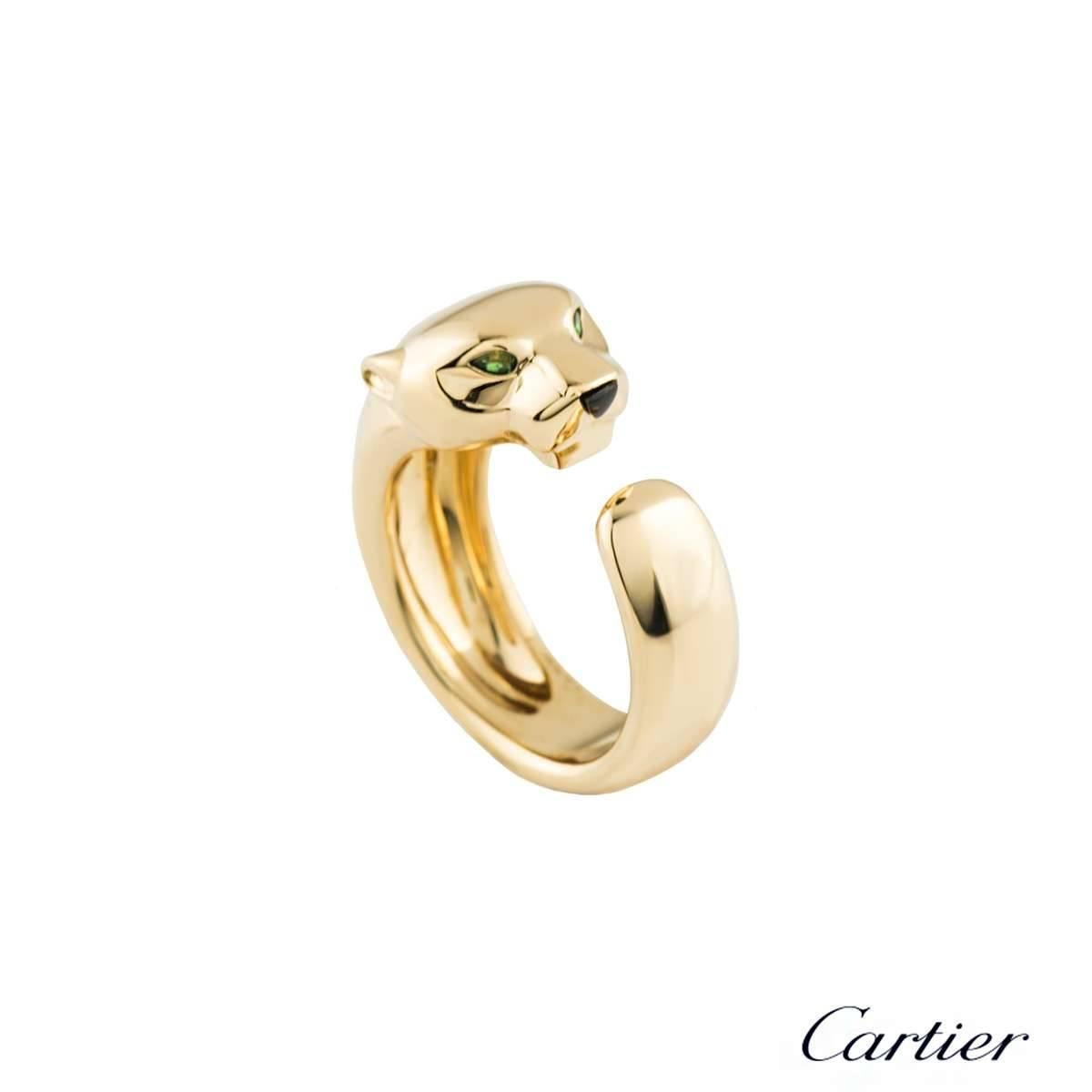 A gorgeous 18k yellow gold Cartier ring from the Panthere De Cartier collection. The ring is composed of a panthere head motif, complimented with 2 tsavorite stones set as the eyes and an onyx as the nose. The panthere body wraps around three