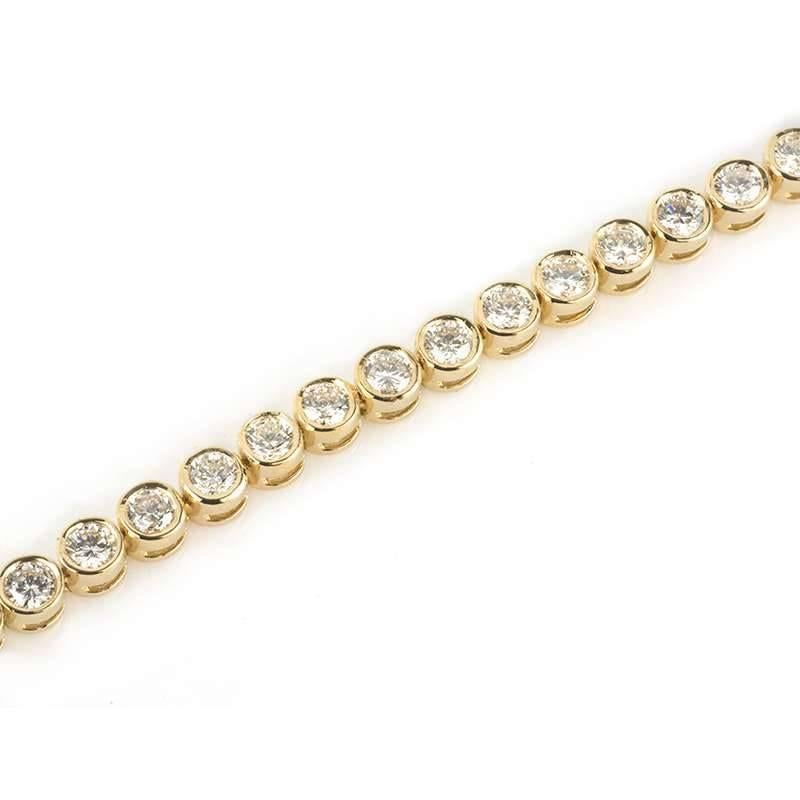 An 18k yellow gold diamond bracelet. The bracelet is composed of 41 round brilliant cut diamonds, each individually rub over set, totalling 4.49ct, predominantly H-I in colour and VS-SI1 clarity. The bracelet measures 7 inches in length and has a