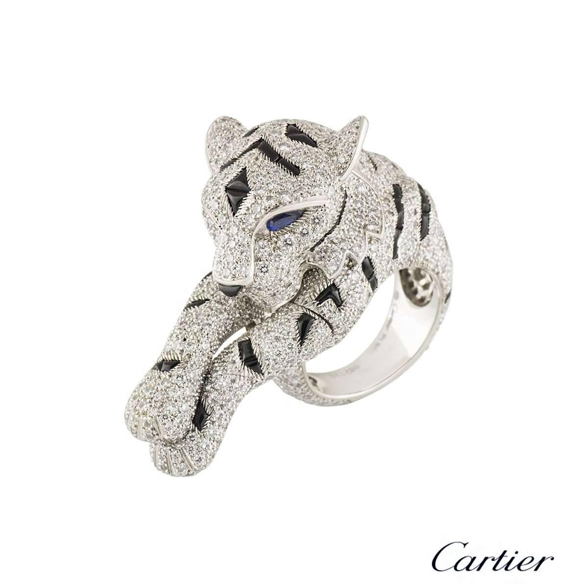 An extraordinary and rare Cartier ring with diamonds, sapphires and onyx dress in platinum from the Pantheré de Cartier collection. The ring comprises of a Panther's head which wraps around the finger, finished off with freely moving paws, giving
