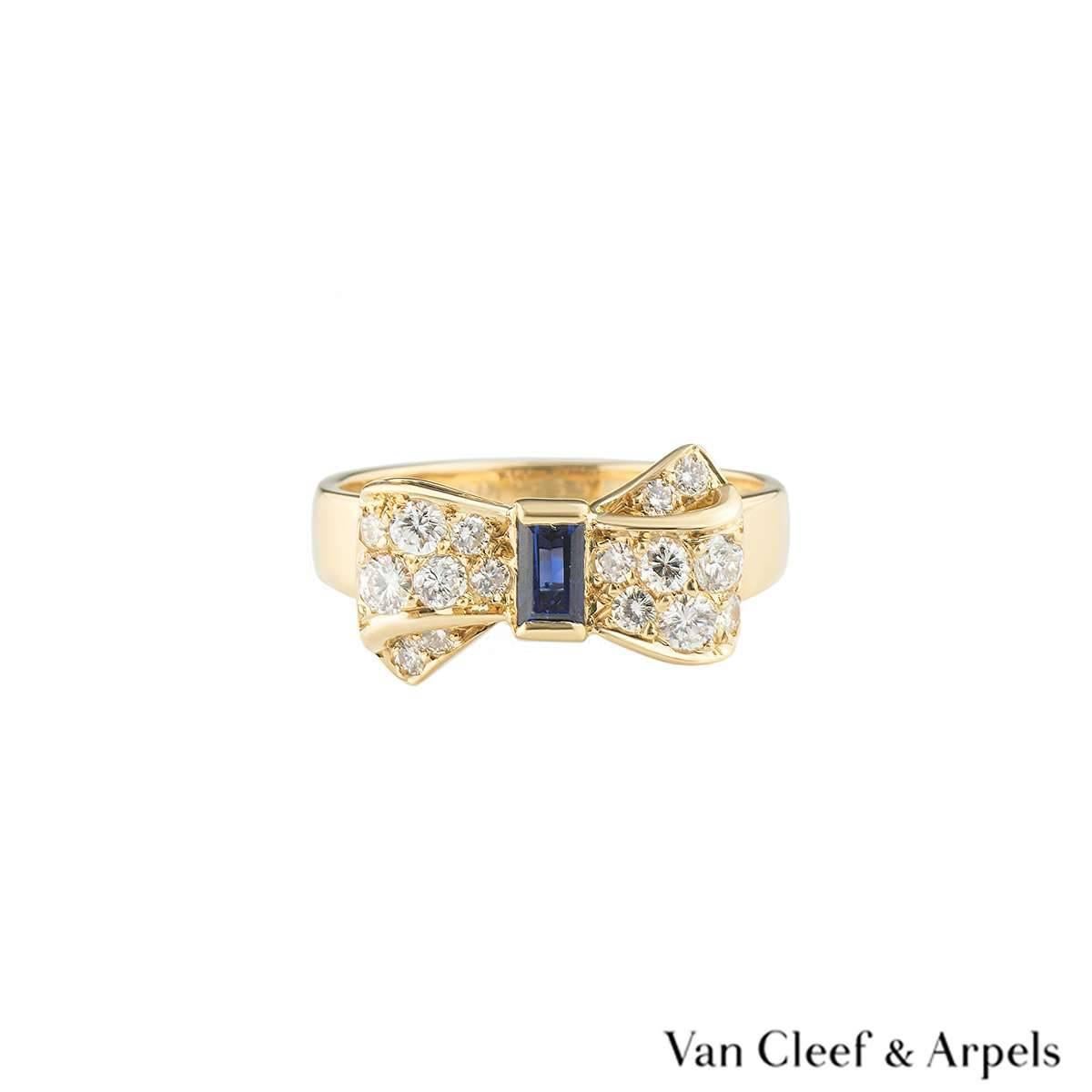 A pretty 18k yellow gold Van Cleef and Arpels dress ring. The ring comprises of a bow motif with a emerald cut sapphire in the centre with a total approximate weight of 0.16ct, with a deep blue hue throughout. On the either side of the sapphire are