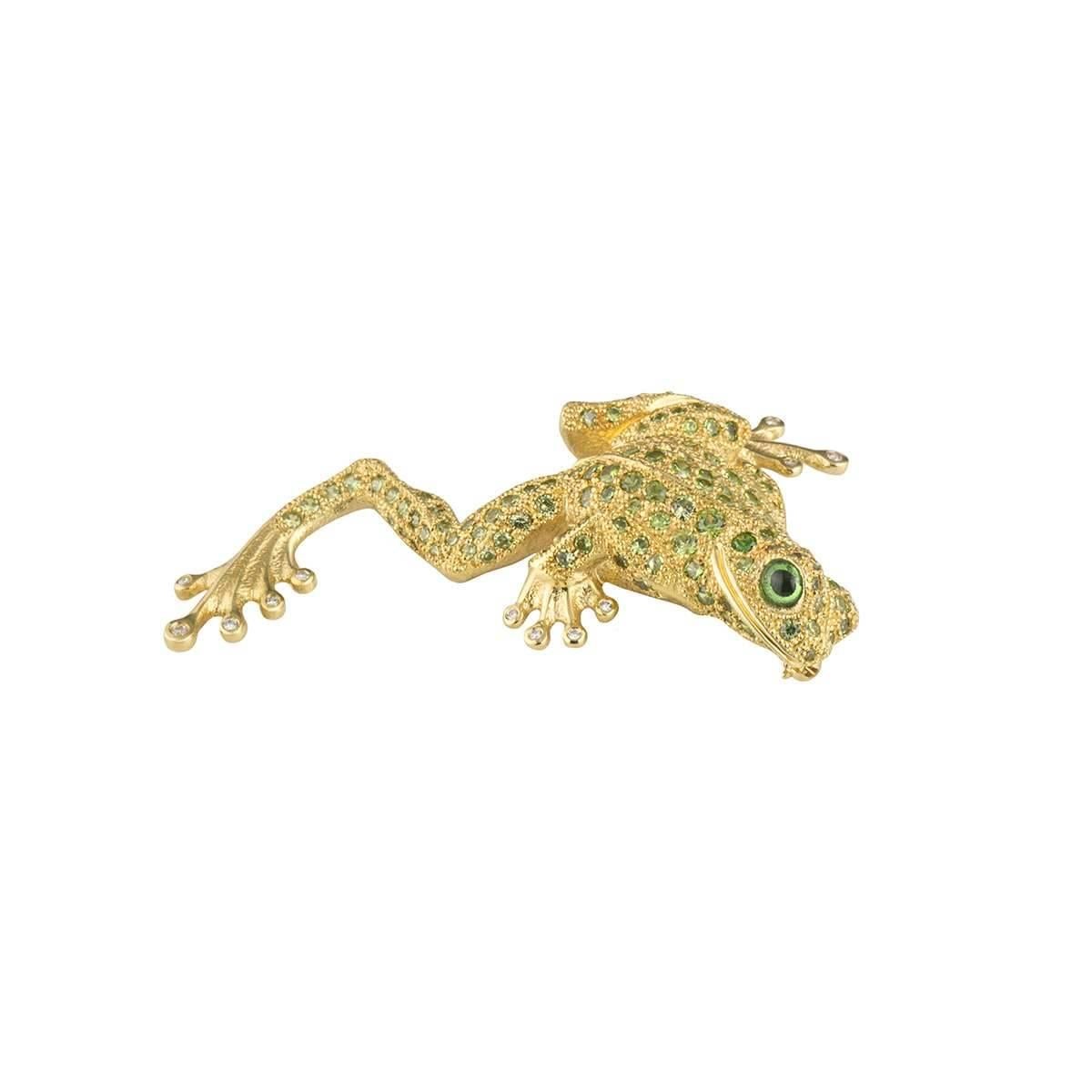 A unique 18k yellow gold diamond and peridot brooch. The brooch comprises of a frog motif pave set with 152 round brilliant cut peridots with a cabachon cut peridot as the frog's eye. The frog shows hands and feet with 13 round brilliant cut
