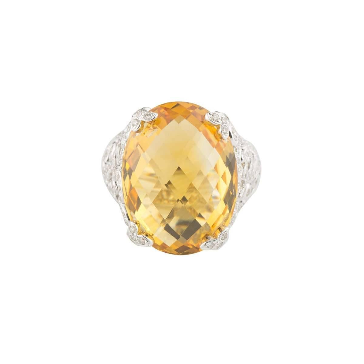 A beautiful 18k white gold diamond and citrine dress ring. The ring comprises of a 15ct oval cut citrine with a orangey-yellow hue throughout. The citrine is complimented with an intricate openwork design with round brilliant cut diamonds, totalling