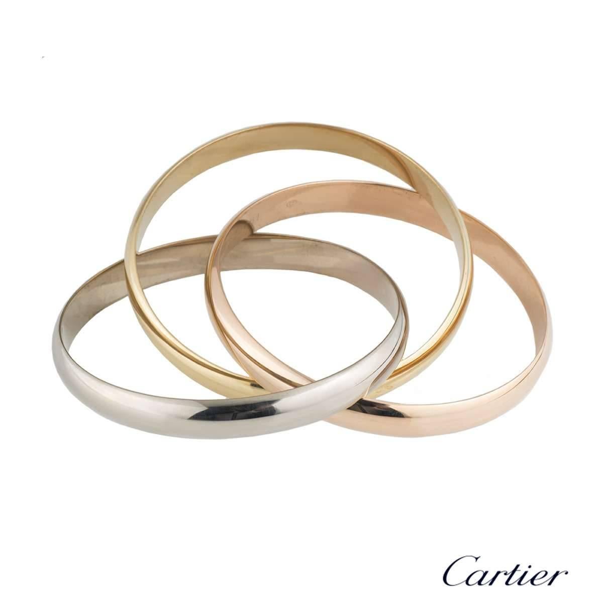 An iconic 18k three colour gold Cartier bangle from the Trinity de Cartier collection. The bracelet is made up of three intertwined 18k rose, white and yellow gold 9mm bands. The bracelet is a large size and has a gross weight of 103.66 grams. 

The