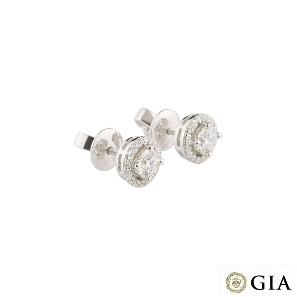 A beautiful pair of 18k white gold diamond earrings. The earrings are each set to the centre with a round brilliant cut diamond weighing approximately 0.40ct, G colour and VS1 clarity. Complimenting the central stone is a halo of 18 round brilliant