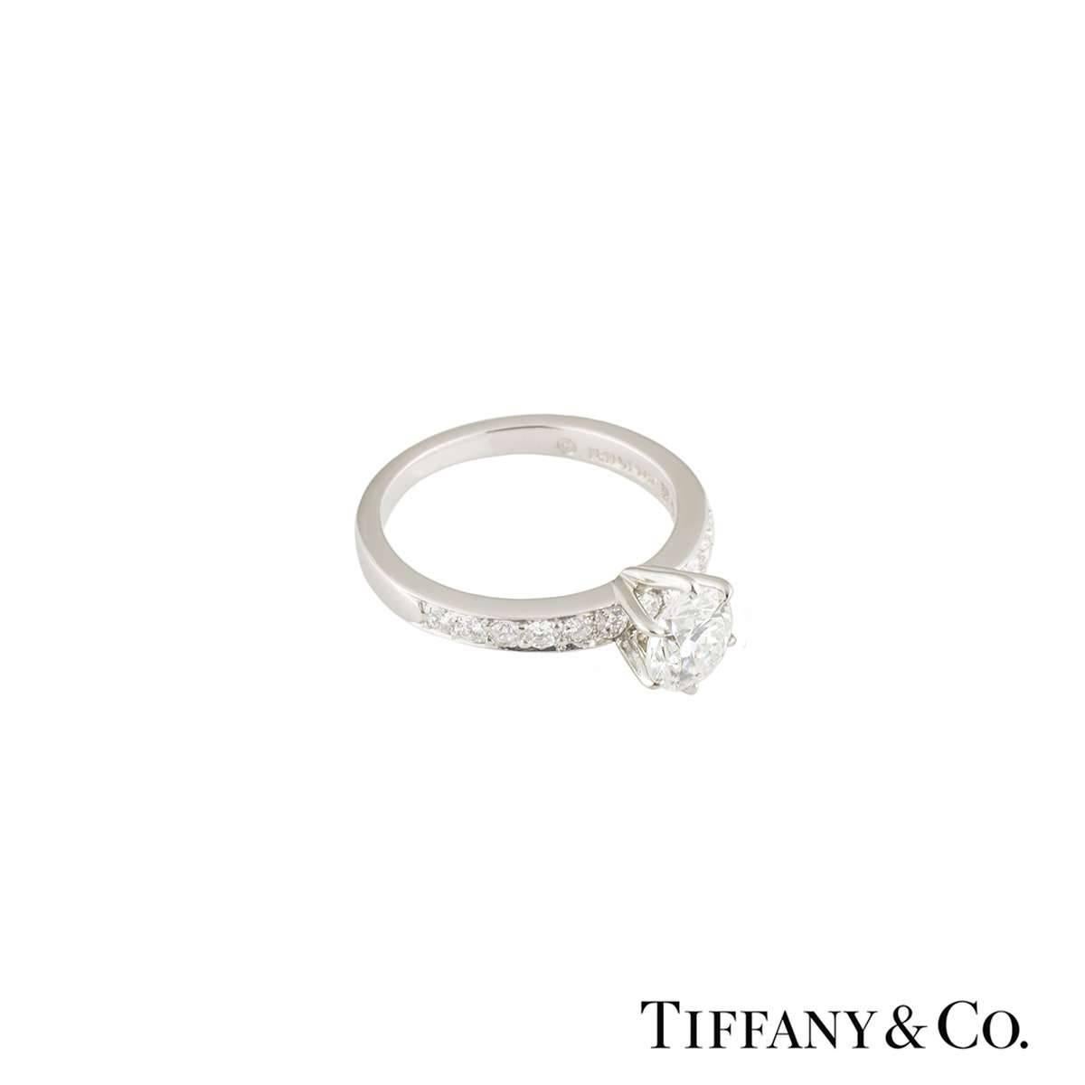 A beautiful Tiffany & Co. diamond engagement ring from The Tiffany Setting with Diamond Band collection. The ring comprises of a round brilliant cut diamonds in a prong setting with a weight of 0.75ct, F colour and VS1 clarity. The ring features