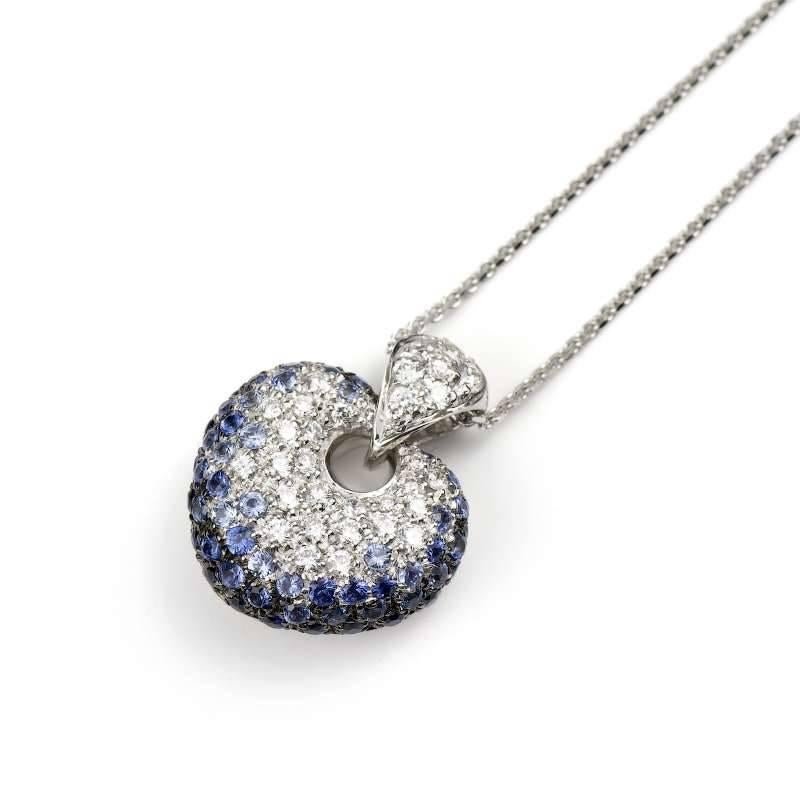 An 18k white gold sapphire and diamond Leo Pizzo pendant. The pendant is formed of a pave set, round brilliant cut diamond heart motif featuring pave set blue sapphires around the lower outer edge. The motif has a total diamond weight of 0.42ct, are