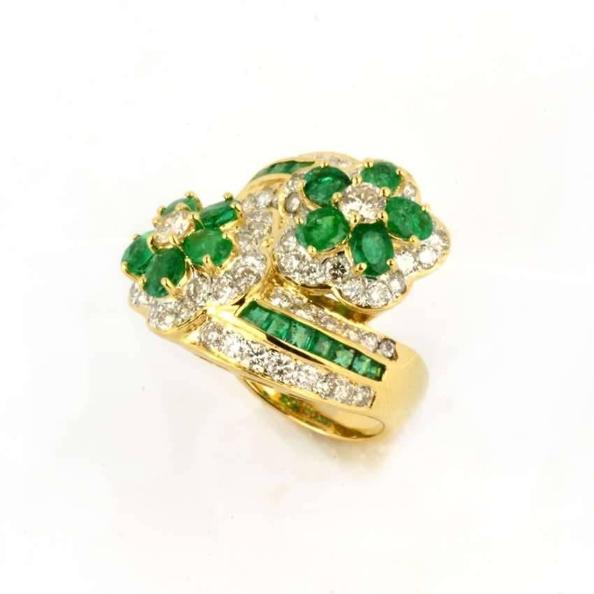 A beautiful 18k yellow gold emerald and diamond floral crossover ring. The ring comprises of two floral sections each made up of 5 pear shaped emeralds and 20 brilliant cut diamonds all in a pave setting, complementing these are the intricate