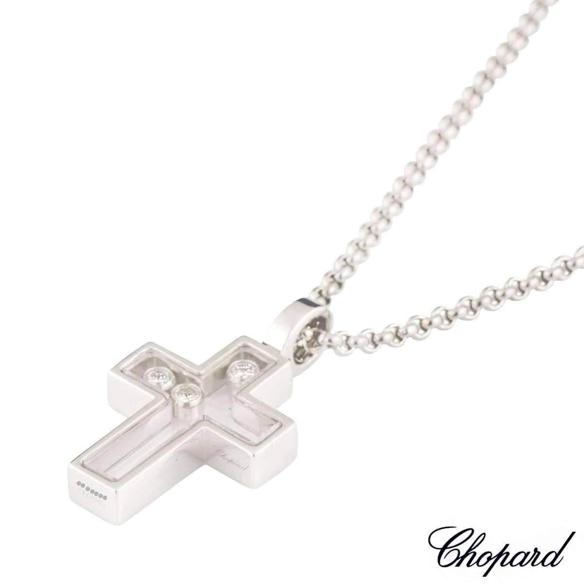 An 18k white gold cross pendant from the Happy Diamonds collection by Chopard. The cross encloses 3 round brilliant cut diamonds totalling 0.17ct in between 2 panels of glass. The cross measures 1.5cm in width and 2.7cm in height including the bale.