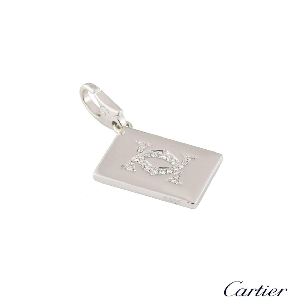 A unique 18k white gold playing card by Cartier. The front of the charm features a Joker playing card; set with diamonds, rubies and onyx. The reverse is encrusted with a diamond double C motif. The diamonds total approximately 0.20ct and the rubies