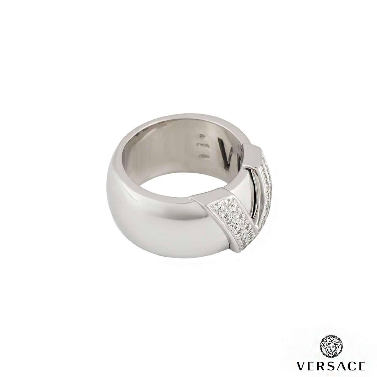 A 18k white gold Versace mens ring. The ring comprises of a V motif with 36 round brilliant cut diamonds in a pave setting with an approximate weight of 0.61ct, G colour and VS clarity. The ring is a D shape and measures 11mm in width. The ring is a