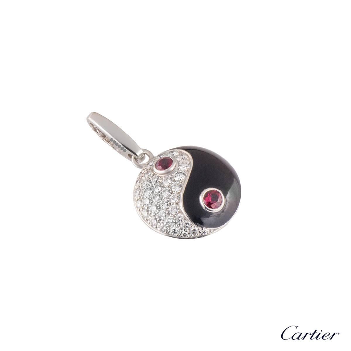 A unique 18k white gold Cartier diamond and ruby charm. The charm comprises of the iconic yin yang motif. The left side is encrusted with 36 round brilliant cut diamonds with a total approximate weight of 0.61ct, D colour and VS+ clarity. There is