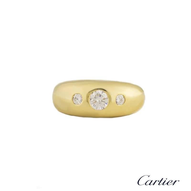 An 18k yellow gold diamond set dress ring by Cartier. The ring is set with 3 round brilliant cut diamonds in a rubover setting evenly spaced, totalling approximately 0.60ct, G/H colour and VS in clarity. The ring is 9mm at the widest point and is