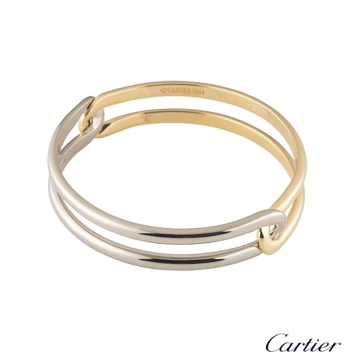 A unique 18k yellow and white gold Cartier bangle. The bangle comprises of a open work double yellow gold and double white gold band interlocking half way round. The bangle measures 13mm in width and fits up to a wrist size of 19cm. The bangle has a